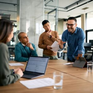 Happy businessman talking to his colleagues during a meeting at corporate office.