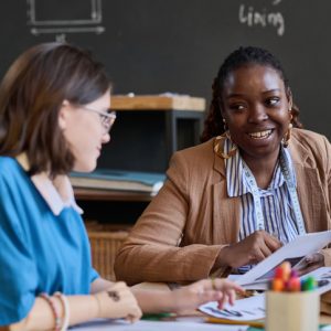 Portrait of smiling Black woman talking to student during sewing class, copy space
