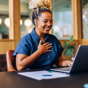 A cheerful young woman participates in an online meeting